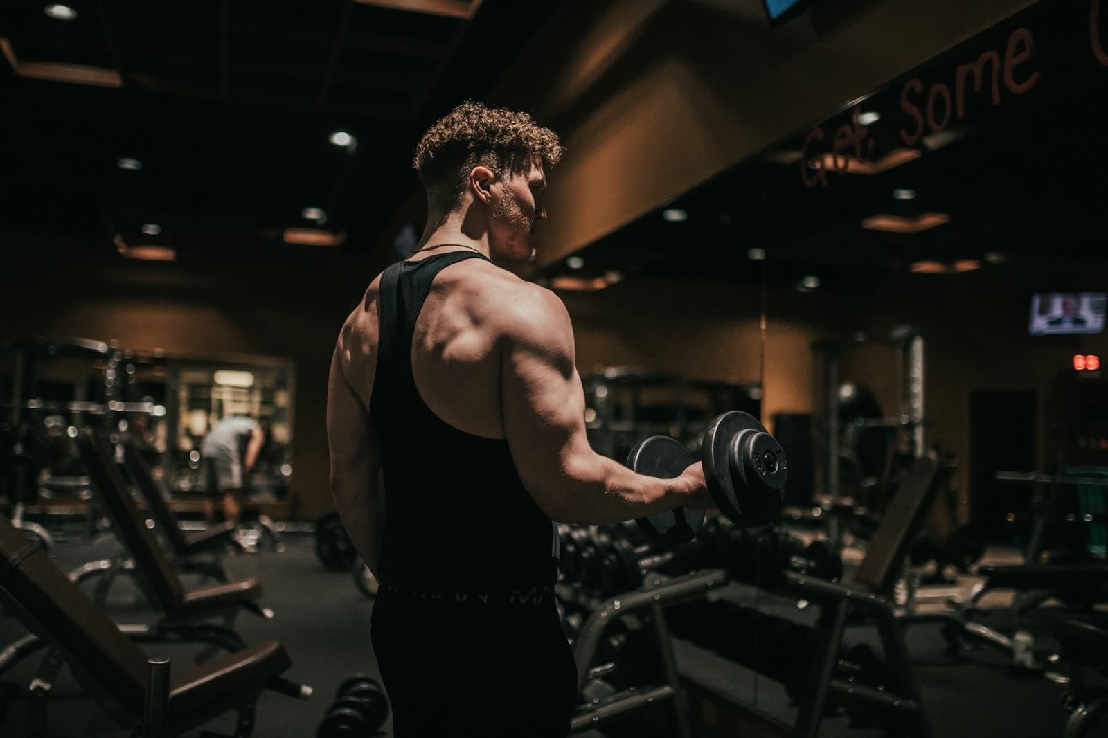 An athletic man curling a dumbbell in the gym